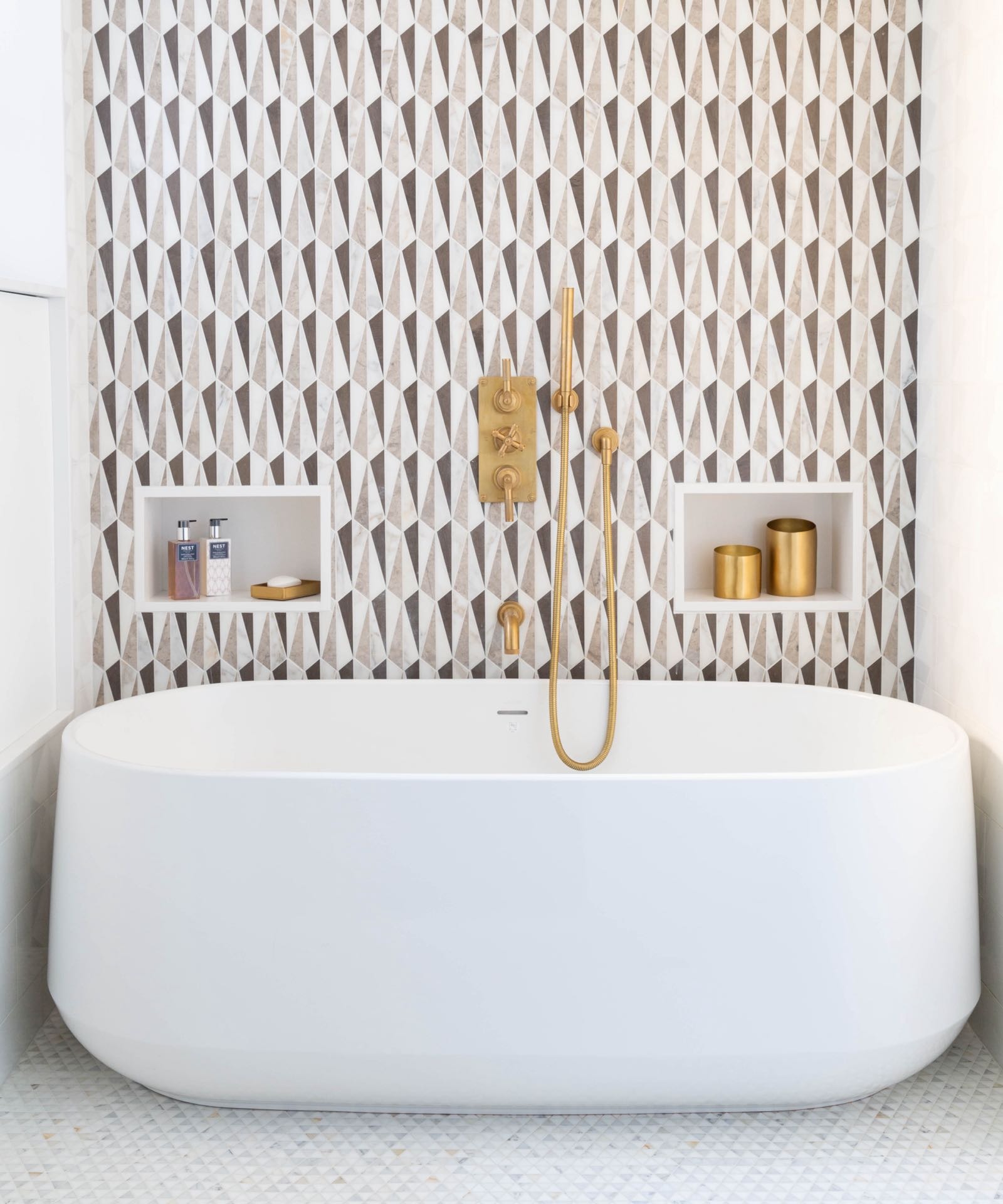 Marble bathroom with brass fixtures and freestanding tub